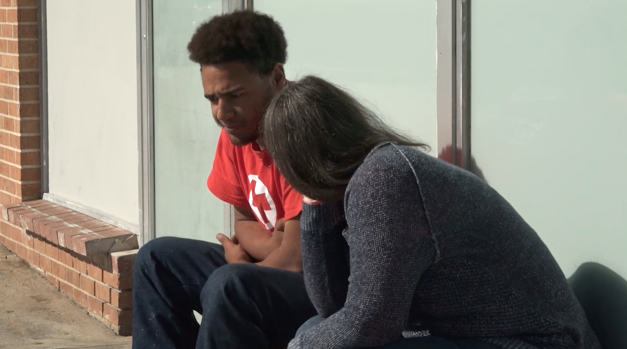 Two people sit outside The Connecting Grounds